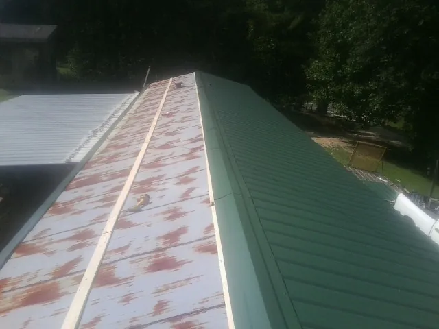 Old rusted panels beside newly installed green metal roofing — Wind Damage Roof Repair by Roofing Brothers in Middletown